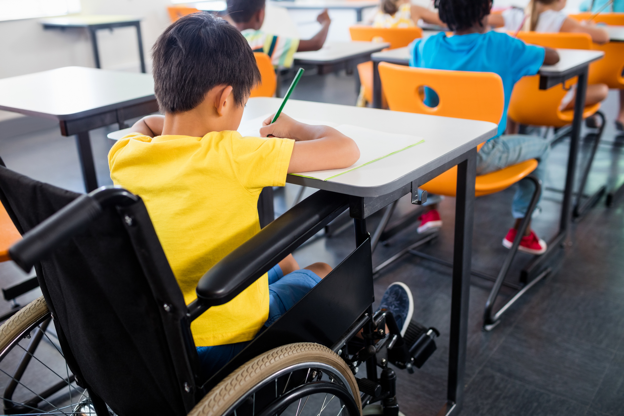 A pupil in wheel chair working at his desk at school